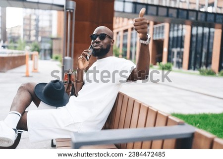 Stylish black man talking on smartphone while making OK finger