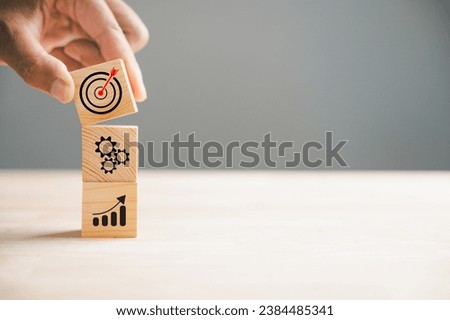 Hand holding and arranging wood blocks in a stacking formation, representing a business strategy and Action plan. This image illustrates the concept of business development and growth.