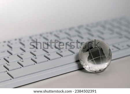 A transparent glass globe in front of the keyboard.Things and Business Concepts. Royalty-Free Stock Photo #2384502391
