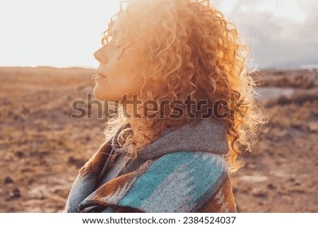 Side view portrait of attractive woman closing eyes and enjoying nature in outdoor leisure activity alone. People and contemplation meditation. Serene lifestyle female person. Long curly healthy hair Royalty-Free Stock Photo #2384524037