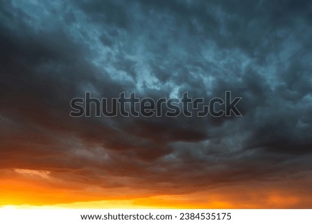 Dramatic sky at sunset, dangerous heavy gray orange color clouds in sky, abstract sky and nature background