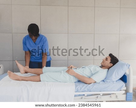 Portrait patient caucasian man with woman nurse carer physical therapist African-American two people sitting talk helping support give advice and holding relax massage on leg body inside hospital 