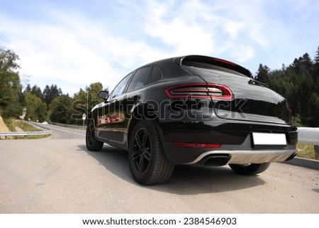 Modern black car parked on asphalt road outdoors