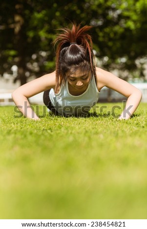 Portrait of healthy young woman doing push ups in park
