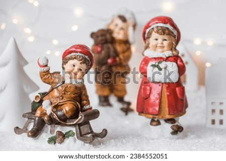Retro Christmas card with cute figures of children on a wooden sled on a snowy background. Beautiful bokeh. The concept of the winter holiday new year 2024.