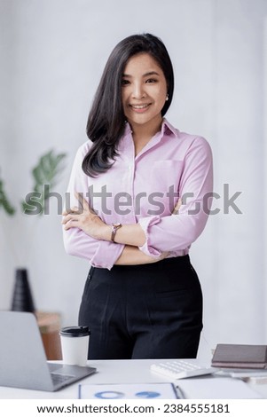 Portrait of Young beautiful positive Asian woman smiling standing in the office Royalty-Free Stock Photo #2384555181