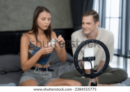 Young woman making beauty and cosmetic tutorial video content for social media using her boyfriend as model and light ring. Beauty blogger showing how to beauty care to audience or follower. Unveiling Royalty-Free Stock Photo #2384555775