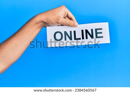 Hand of caucasian man holding paper with online word over isolated blue background