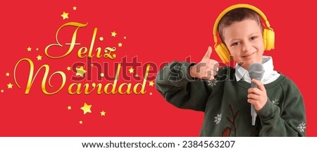 Cute little boy with microphone showing thumb-up and text FELIZ NAVIDAD (Spanish for Merry Christmas)  on red background