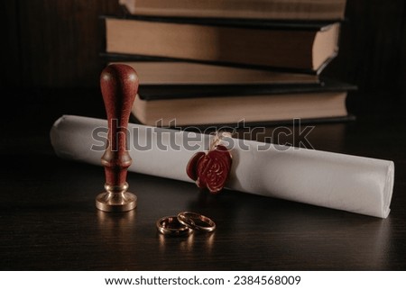 Marriage contract with seal and golden rings in a courtroom close-up. Family and law concept. Royalty-Free Stock Photo #2384568009
