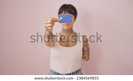 Hispanic woman with amputee arm holding credit card over isolated pink background