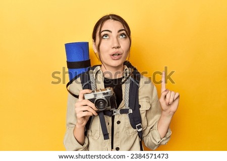 Photographer with gear ready to explore pointing upside with opened mouth.