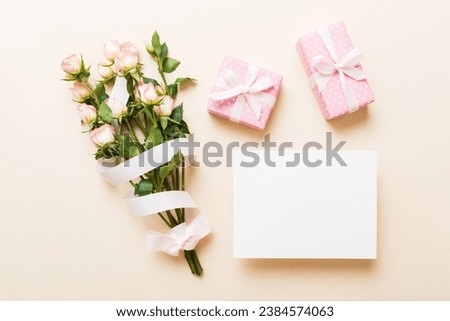 Greeting holiday card mockup with fresh roses on colored table background, mock up with copy space for design.