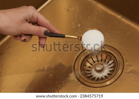 Cleaning kitchen sink with bakIng soda to keep sinks draining well and prevent clogs. Safe, effective, cheap, natural solution for clogged drains. Royalty-Free Stock Photo #2384575719
