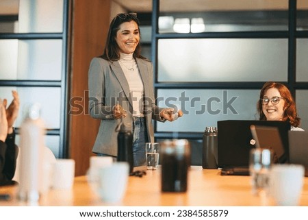 Business professionals engage in a collaborative discussion in a bright boardroom. The diverse team, including women leaders, share creative ideas, fostering a positive and successful work environment Royalty-Free Stock Photo #2384585879
