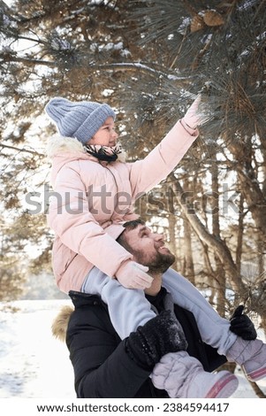 Happy family in the winter forest. High quality photo. A father holds his daughter around his neck in a winter forest. Tiredness from walking.