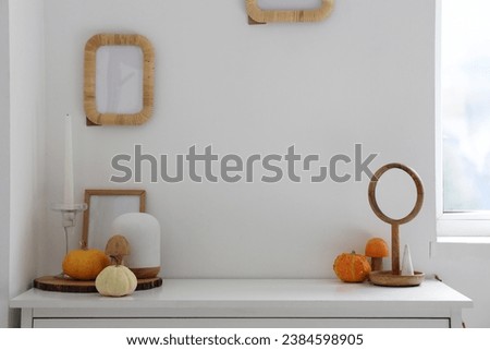 Pumpkins with frame and lamp on shelf in room