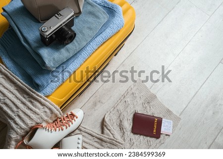 Suitcase with winter clothes and accessories on floor, top view