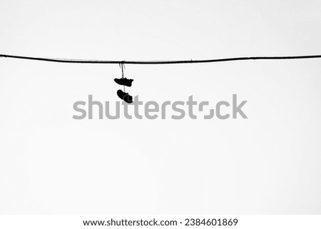 black silhouette of sneakers, Shoes hanging from a telephone wire on white sky background. Old sneakers hang on an electric wire on a summer day.  isolated on white background. illustration. 