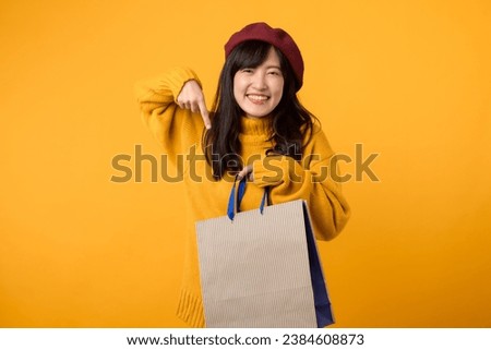 Young Asian woman 30s, wearing a yellow sweater and red beret, enjoys a shopping adventure against a vibrant yellow backdrop.