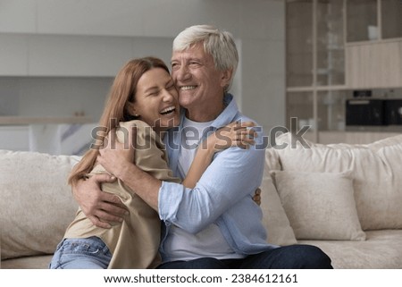 Laughing excited woman cuddle older father, loving multigenerational family enjoy reunion after long separation, hoary man hugs his grown up daughter visited him at home, feeling unconditional love Royalty-Free Stock Photo #2384612161