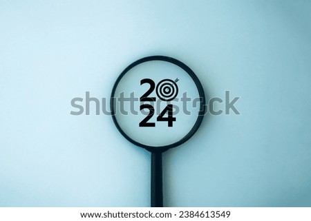 Happy new year 2024 business concept. 2024 number with target icon inside the magnifying glass on blue background