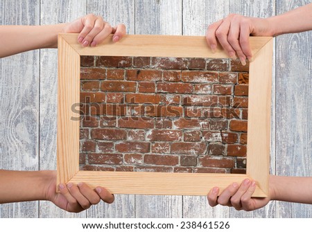 Close up of human hands holding wooden frame with brick texture