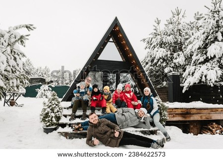 Big family with kids on terrace of mountain country house in snow forest together. Best friends in casual clothes spend winter holidays at cottage. Company people childs on vacation celebrate New Year