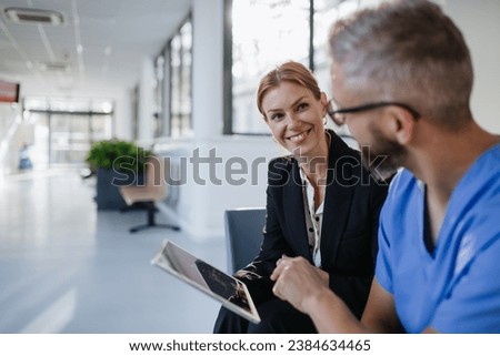Pharmaceutical sales representative talking with doctor in medical building. Ambitious female sales representative presenting new medication. Woman business leader. Royalty-Free Stock Photo #2384634465