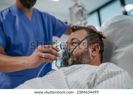 Nurse fitting oxygen mask on patient in hospital bed. Man in intensive care unit in hospital. Royalty-Free Stock Photo #2384634499