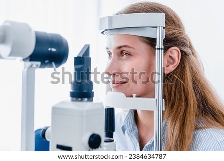 Young woman patient undergoing ophthalmic vision check up with slit-lamp retinoscope modern apparatus in clinic hospital. : side view. Ophthalmology concept Royalty-Free Stock Photo #2384634787
