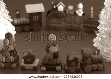 A toy Christmas train made of plasticine with gifts and Christmas trees. Black and white background. New Year decorations.