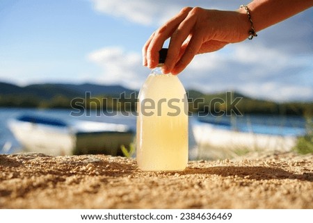 Probiotic and refreshment lemon drink. Homemade fermented kombucha tea in a glass bottle with a lake of background.