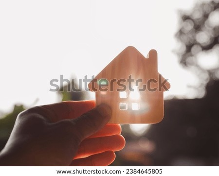 Silhouette of Businessman holding Wooden house model on wood background, a symbol for construction , ecology, loan, mortgage, property or home.