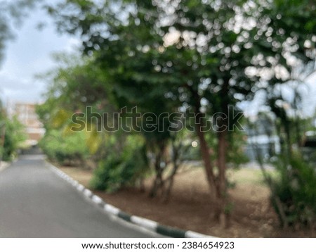 The road is in a beautiful residential area with lots of trees on either side on blurred background