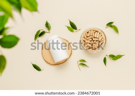Vitamins medical bottle mockup on wooden podium with pills and green leaves, organic medication. Natural herbal supplement, healthy lifestyle, top view Royalty-Free Stock Photo #2384672001