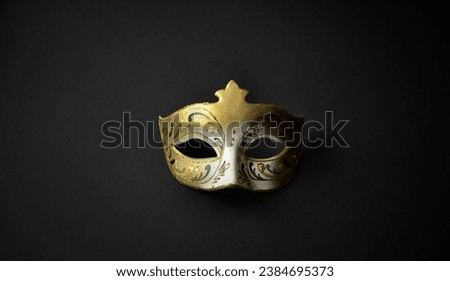 Gold tone Venetian carnival colombina mask with painted ornaments. Minimal composition - a mask on a black background