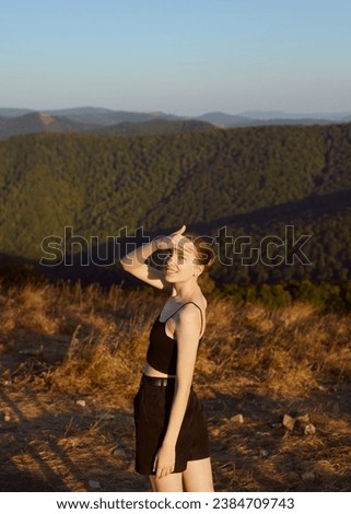 a beautiful, slender woman is resting in the mountains, standing in summer clothes