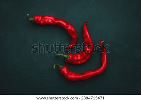 Fresh red hot chili peppers on deep green background, minimalistic style, vegetable art, top view