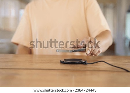 Charging mobile phone battery with wireless charging device in the table. Smartphone charging on a charging pad. Mobile phone near wireless charger Modern lifestyle technology concept