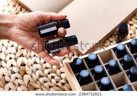 Woman's hand takes out a bottle of essential oil from a wooden box. essential oils in wooden box. Herbal alternative medicine with essential oils bottles in wooden box, healthy organic natural therapy Royalty-Free Stock Photo #2384732821
