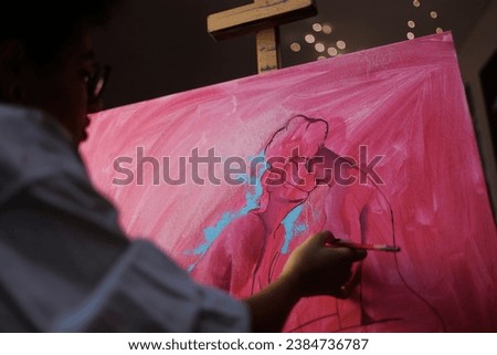 Blurred african american artist painting on canvas on easel in studio in evening	