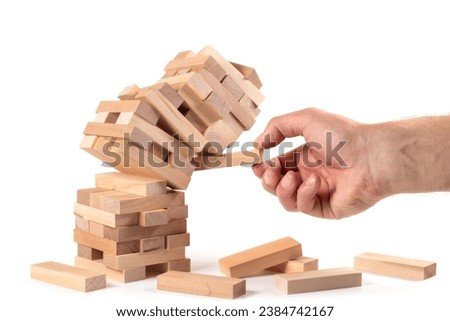 Businessman removing wooden block from falling tower on table. Management of risks and economic instability concept with wooden jenga game. Failure and collapse in corporate business Royalty-Free Stock Photo #2384742167