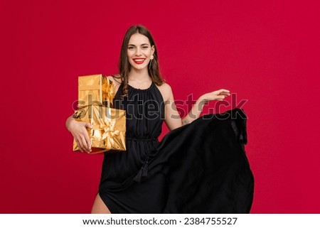 attractive woman in black dress celebrating black friday sale and Christmas on red background with golden present box happy smiling long hair stylish fashion trend sale