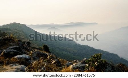 Mountain Top in the clouds over flowing fog between mountain peaks. Clouds drift amid rocky cliffs. Picture of a mountain top from above the clouds. Top view of mountain valley in low clouds