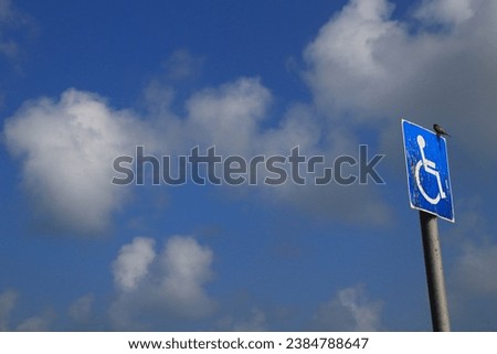 Handicap sign with bird and cloudy sky