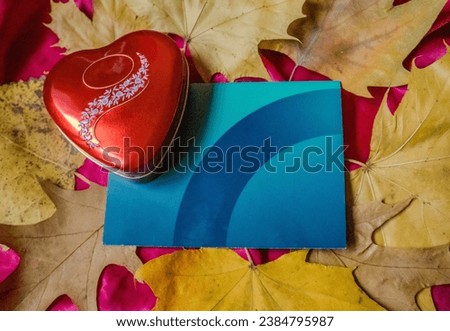 Present of Valentine on pink silk. Red heart with surrounded by autumn leaves
