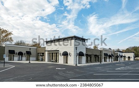 Newly constructed strip mall in neutral tones of black and tans with black awnings. Royalty-Free Stock Photo #2384805067