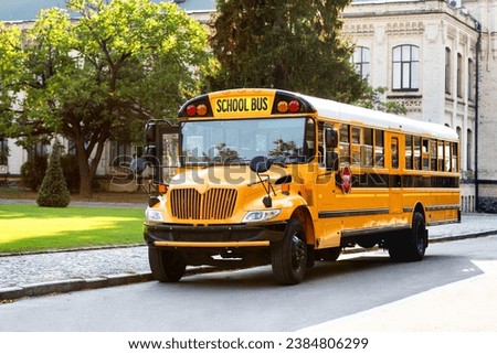 Classic yellow school bus with its red stop sign standing on the road, retro vehicle awaiting students on the parking area, ready to pick up pupils, transportation concept, copy space Royalty-Free Stock Photo #2384806299