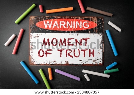 Moment of truth. Metal warning sign and colored pieces of chalk on a dark chalkboard background. Royalty-Free Stock Photo #2384807357